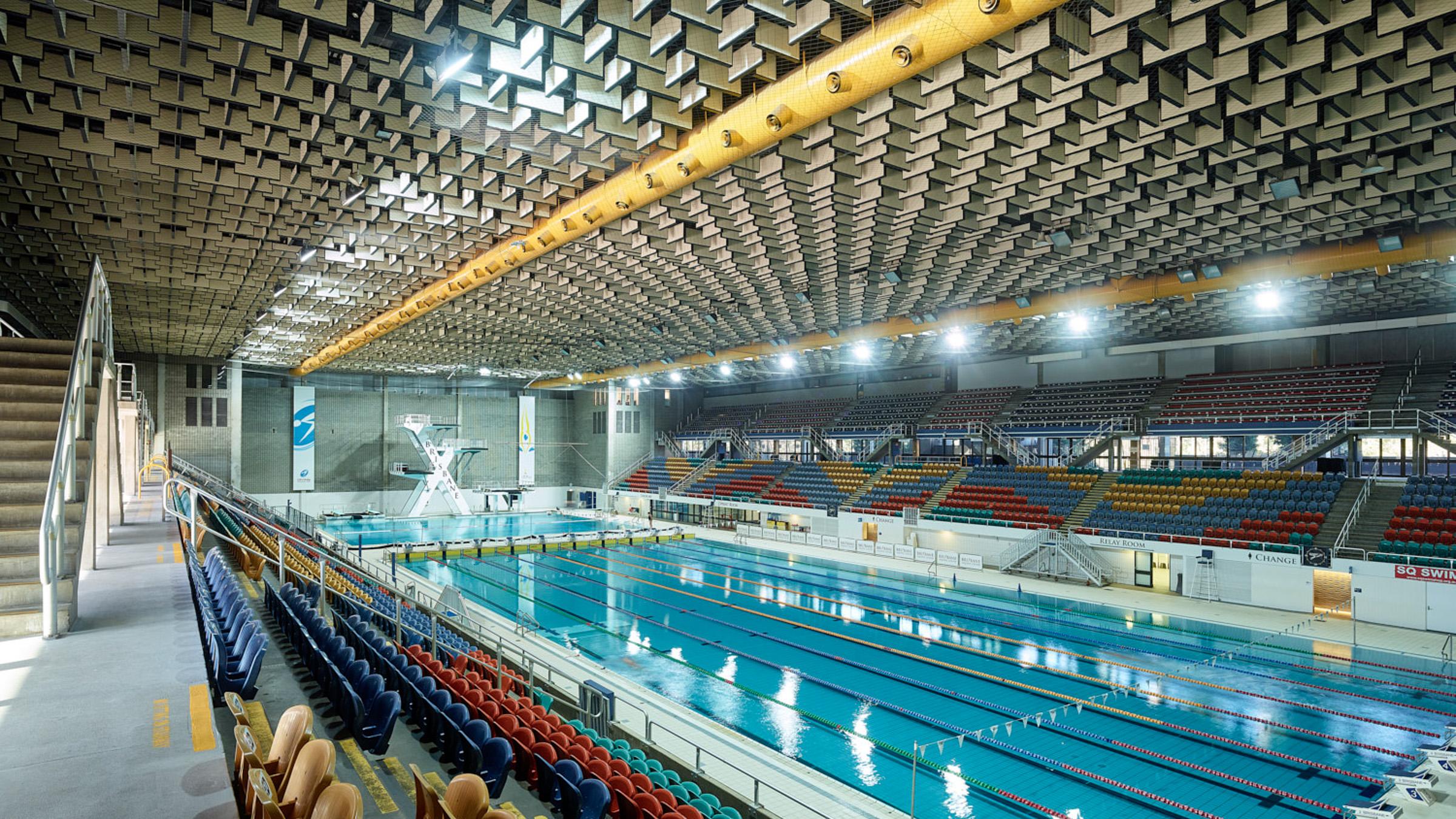 Indoor view of Brisbane Aquatic Centre with Olympic-sized swimming pool, diving boards and spectator stands